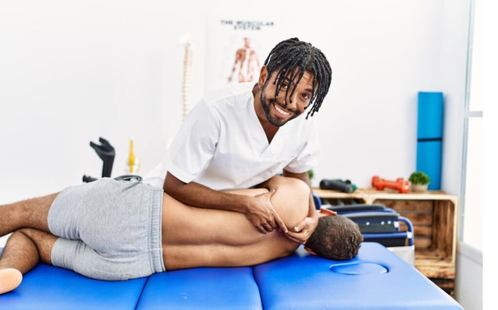 A smiling chiropractor is working on a male patient's leg