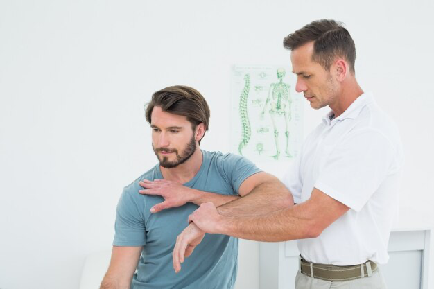 Male physiotherapist extending hand to young man