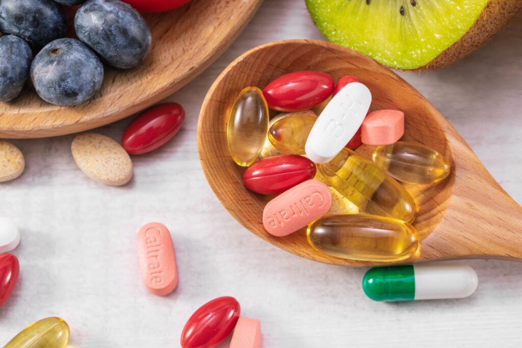 Top view of fresh fruits with different medicine on a wooden spoon