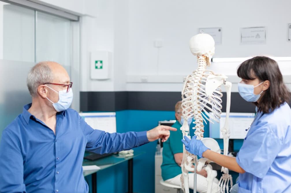 Health professionals discuss a skeletal model's anatomy